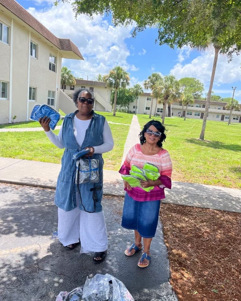Two women from the ministry stand outside an apartment complex holding bags of supplies to hand out.
