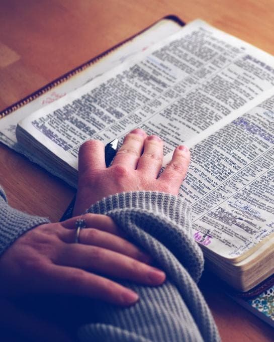 Hands resting on an open Bible.